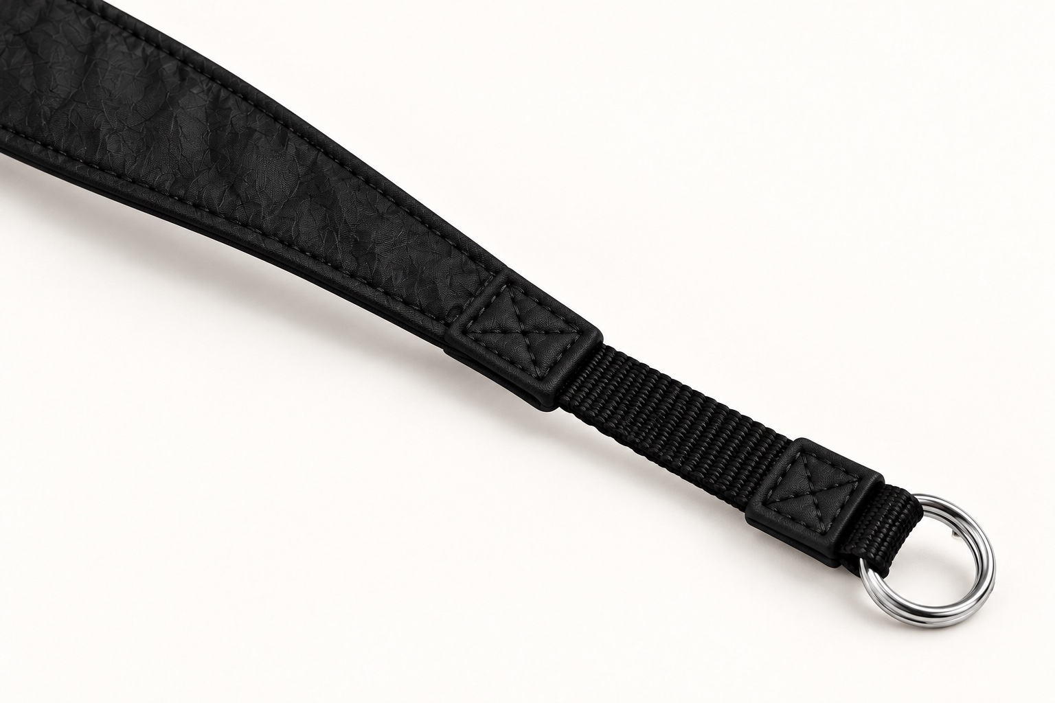Close-up of the camera strap taper, fabric stitching, narrow webbing and split-ring attachment.